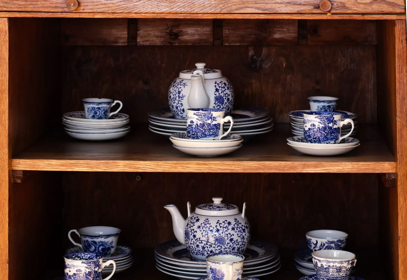 Juegos de té de porcelana azul y blanca ordenados en una vitrina